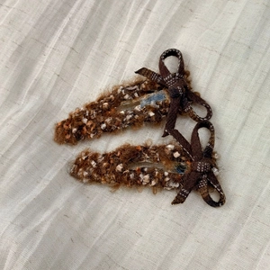 Close-up of plush coffee brown bow hair clips with glitter threads on linen background