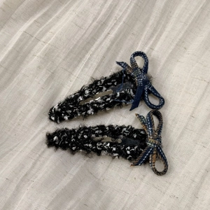 Close-up of elegant black and white tweed hair clips with blue plaid ribbon bows
