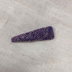 Detail of purple tweed fabric triangular hair clip with woven texture on white base
