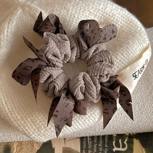 Brown ribbed fabric scrunchie with leopard print ribbon on a cozy knit hat