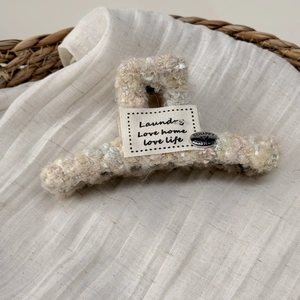 Detail of plush knit hair claw clip with woven tag and silver smile button