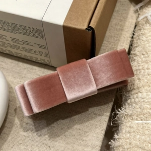 Close-up of a dusty pink velvet bow hair clip showing soft fabric layers and texture