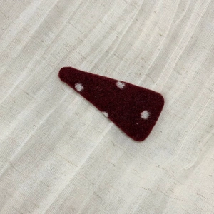 Detail of red polka dot fabric hair clip on a textured linen background