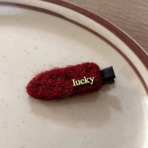 Primer plano de pinza de pelo de felpa roja con letras lucky doradas en un plato