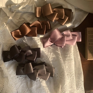 Set of large satin bow hair clips in neutral earth tones on a lace background