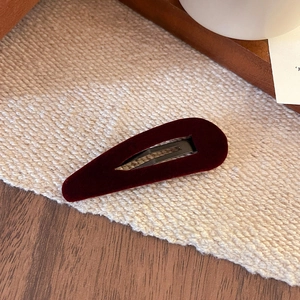 Close-up of a vintage wine red velvet BB hair clip on textured fabric background