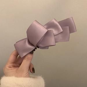 Elegant light purple satin layered bow hair clip held by hand for a stylish hair look