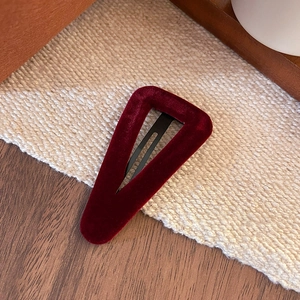 Detailed macro view of a vintage dark red velvet triangle BB hair clip with metal grip