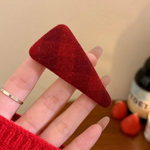 Close-up of a red plaid fabric triangle hair clip with winter textured grid pattern