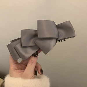 Close-up of layered grey satin bow hair clip with elegant silk texture and secure grip