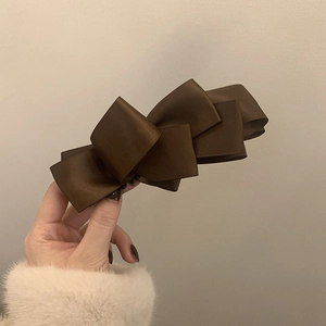 Detailed view of the layered dark coffee satin bow clip with silk luster texture