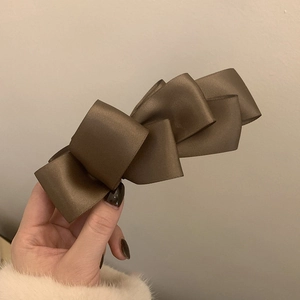 Detail of elegant large brown satin ribbon banana clip held against a soft background