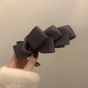 Detailed view of the layered satin ribbon bow on the dark vertical banana hair clip
