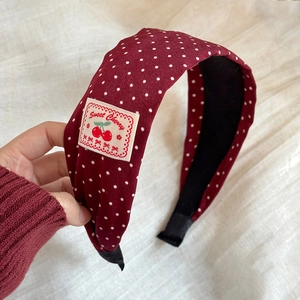 Close-up of red polka dot headband featuring Sweet Cherry label and premium fabric texture