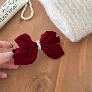 Close-up of burgundy velvet bow hair clip with luxury rhinestone center and metallic spring