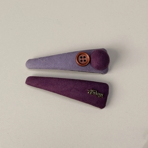 Détail de barrettes en tissu violet avec bouton vintage et breloque dorée Always en métal