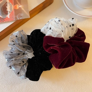 Three-piece set of velvet and mesh polka dot hair scrunchies on a cozy desk