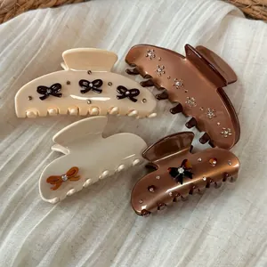 Set of four vintage acetate hair claws with rhinestones and black bows in cream and brown