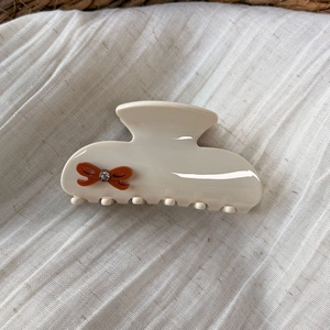 Detailed close-up of cream hair claw clip with a brown bow and sparkling rhinestone