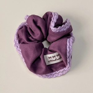 Détail d'un chouchou tricoté violet fait main avec bordure au crochet et étiquette logo