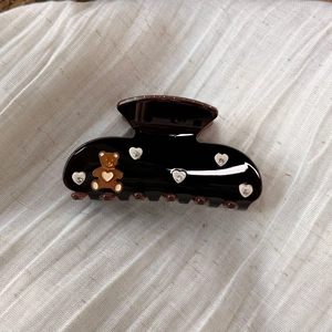 Macro detail of large brown hair claw clip with bear and rhinestone heart accents