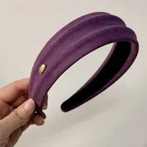 Détail du bandeau tricoté violet avec étiquette dorée 'Hand made' et tissu texturé