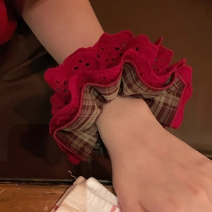 Detail of red lace and plaid scrunchie worn on wrist showing embroidery edges