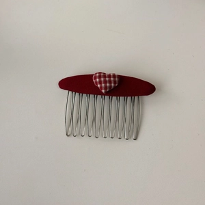 Dettaglio di un pettine per capelli vintage con cuore a scacchi rossi e denti in metallo