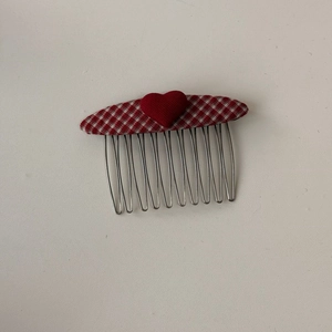 Dettaglio pettine per capelli a quadretti rossi e bianchi con cuore su base in metallo