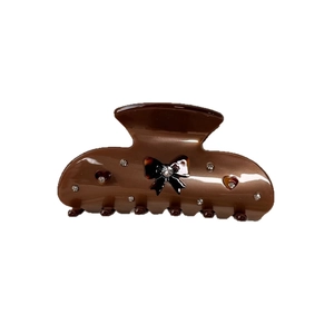 Brown acetate hair claw clip with rhinestone bow and hearts on white background