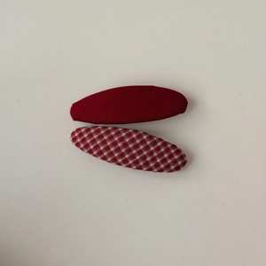 Dettaglio delle mollette BB in tessuto a righe rosse e a quadretti su sfondo beige