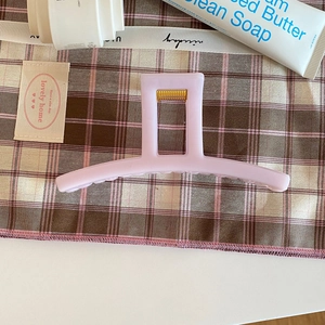 Détail d'une grande pince à cheveux carrée lilas mat sur un fond en tissu élégant et épuré