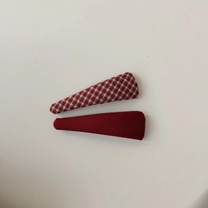 Dettaglio di un set di fermagli per capelli in tessuto a quadri rossi e rosso scuro