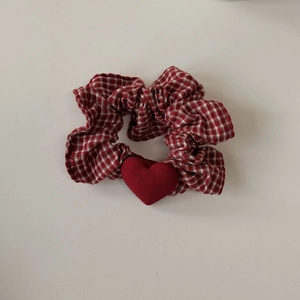 Dettaglio di elastico per capelli a quadretti rossi e bianchi con ciondolo a cuore