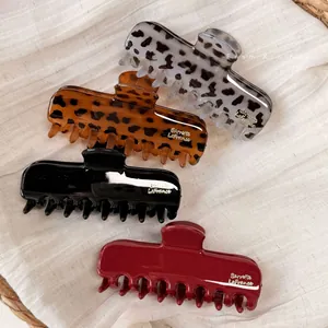 Close-up of four assorted hair claws in tortoiseshell, red, and black on a white fabric base
