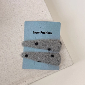 Close-up of gray wool felt hair clips with black polka dots on blue display card