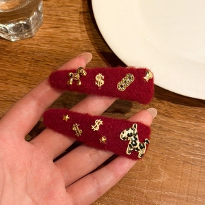 Set di due fermagli rossi in peluche con ciondoli dorati e simboli di buona fortuna
