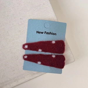 Close-up of red felt hair clips with white polka dots on a New Fashion display card