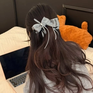 Dettaglio del fermaglio per capelli a fiocco grigio con nappa e strass su capelli
