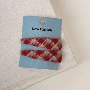 Detail shot of two red plaid fabric hair clips on a blue display card for autumn style