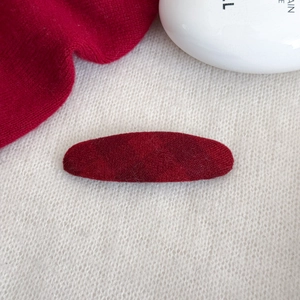 Elegante fermaglio per capelli ovale in velluto rosso vino su sfondo in maglia bianca