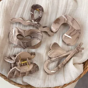 Set of five tortoiseshell hair claws and clips in marble brown on neutral linen background