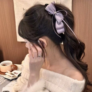 Dettaglio del fermaglio per capelli a fiocco viola con tessuto glitterato e strass su capelli