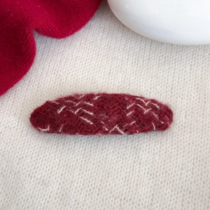 Dettaglio di un fermaglio per capelli in maglia rosso scuro con trama vintage