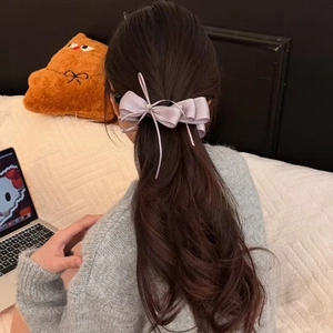 Dettaglio di un fermaglio per capelli a doppio fiocco in raso viola su capelli mossi