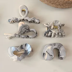 Flat lay of five marble grey hair claws in various shapes with golden springs