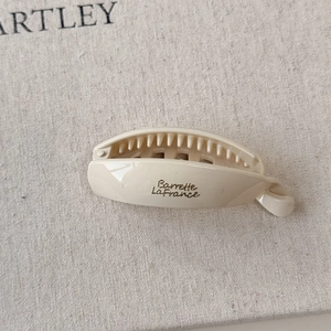 Close-up of ivory resin banana hair clip with gold lettering and comb teeth detail