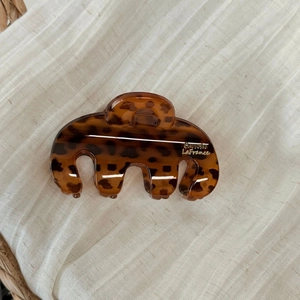 Detail of tortoise shell hair claw clip with golden Barrette La France text on white fabric