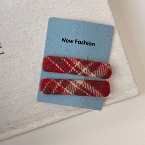 Detail shot of red plaid BB hair clips in classic Scottish tartan fabric on a display card