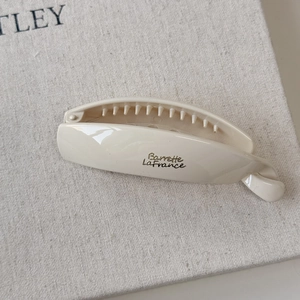 Detail of minimalist cream resin banana clip with golden Barrette La France text